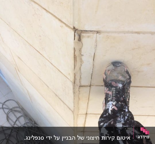 אדם עומד על קיר עם סדק ותיקון איטום